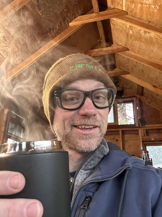Ry Smith smiling and holding up a cup of coffee in a friendly, cheers-style way